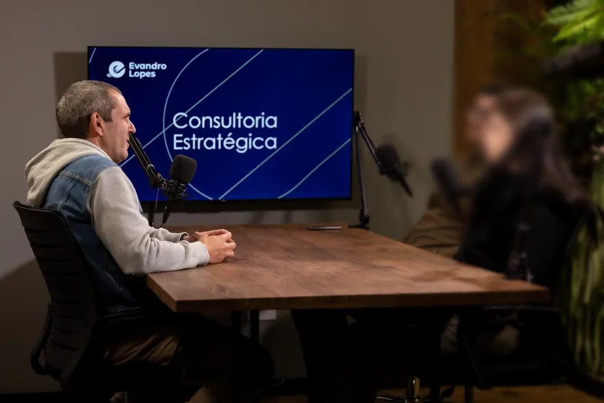 Evandro Lopes em uma mesa de estúdio, em conversa gravada, com o plano de trás fora de foco